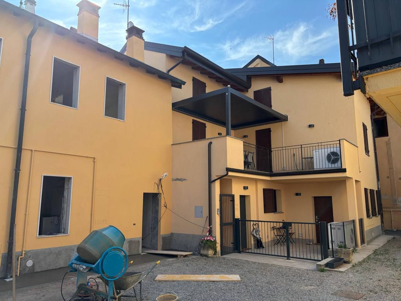 Una casa ristrutturata da noi: facciate gialle, balcone con ringhiera nera e pergola sul cortile