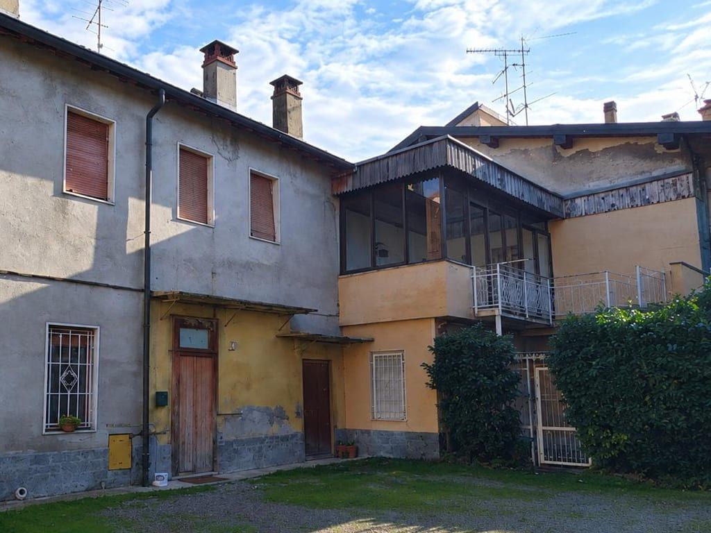 Prima: il vecchio edificio sul cortile, con le facciate grigie e scrostate, la veranda in legno e le ringhiere bianche